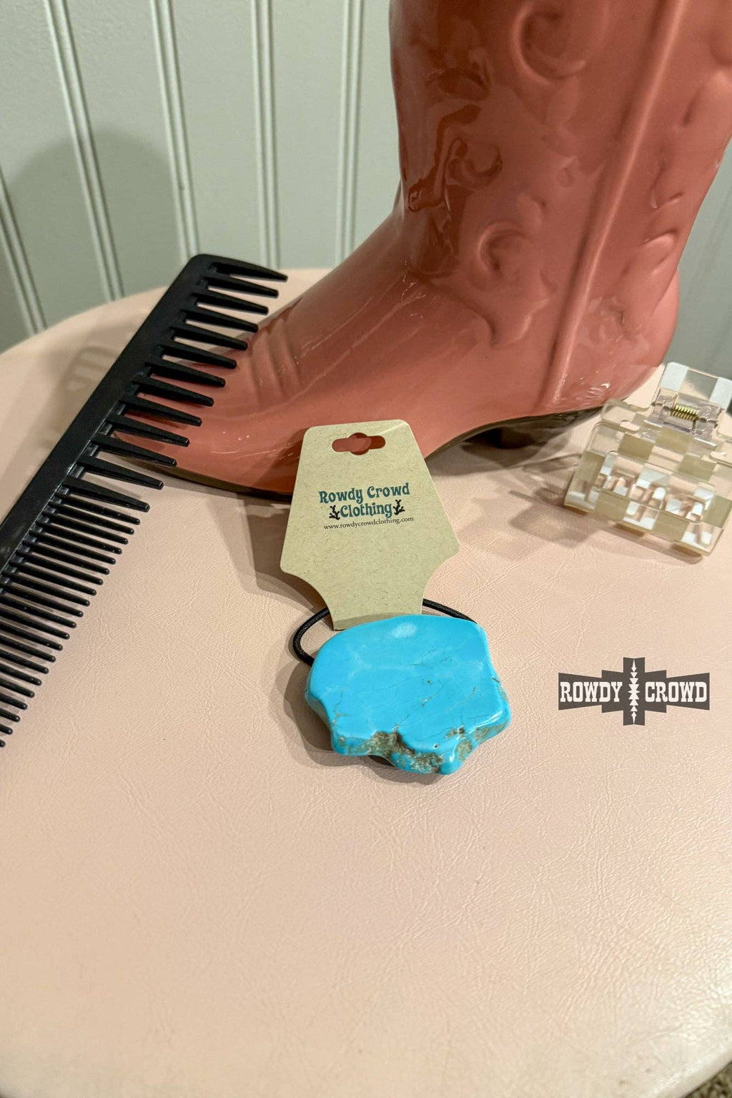 Turquoise Rock Ponytail Holder displayed next to a comb and pink cowboy boot on a tabletop.