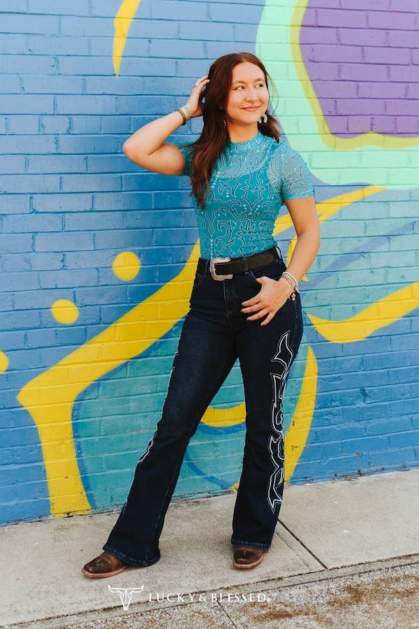 Woman wearing Plus Dark Wash Tummy Control Boot Stitch Embroidery Jeans against colorful mural background.