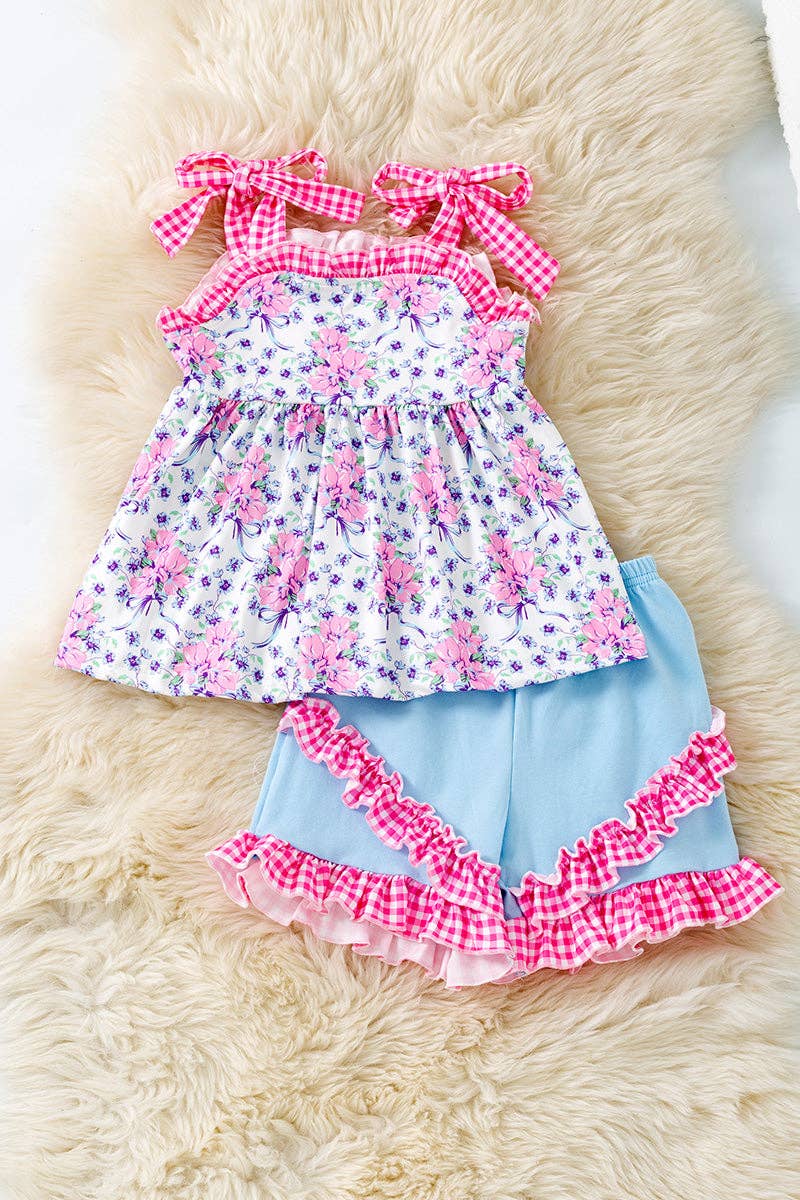 Purple/pink floral tunic with gingham straps and blue shorts.