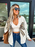 Leopard Bow Sand Graphic Cardigan worn by a fashionable woman with blonde hair, sunglasses, and a smile.