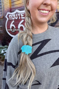 A woman wearing a Turquoise Rock Ponytail Holder in her braided hair, showcasing the vibrant turquoise accessory.