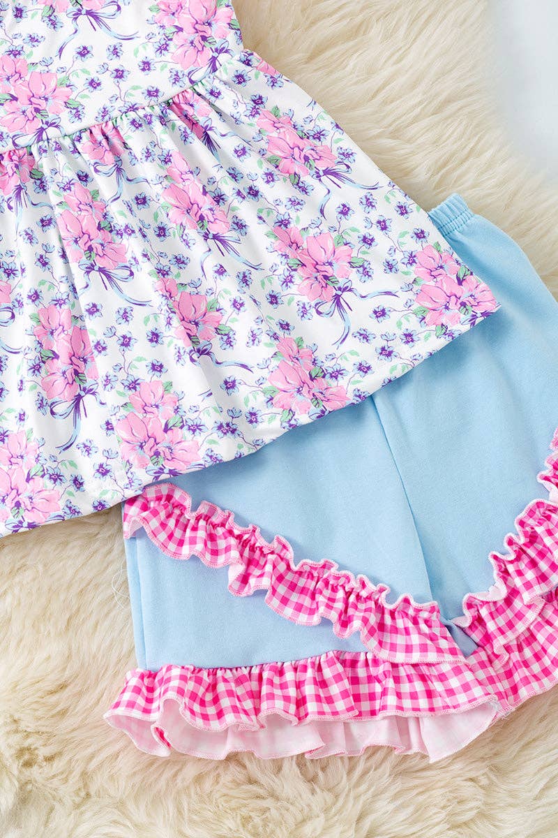 Purple/pink floral tunic with gingham straps and blue shorts.